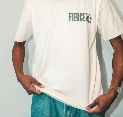 Model wears ecru Fierce Mild non-alc beer merchandise t-shirt. Image focuses on t-shirt, with blue jeans sof model shown only slightly at bottom of photograph.